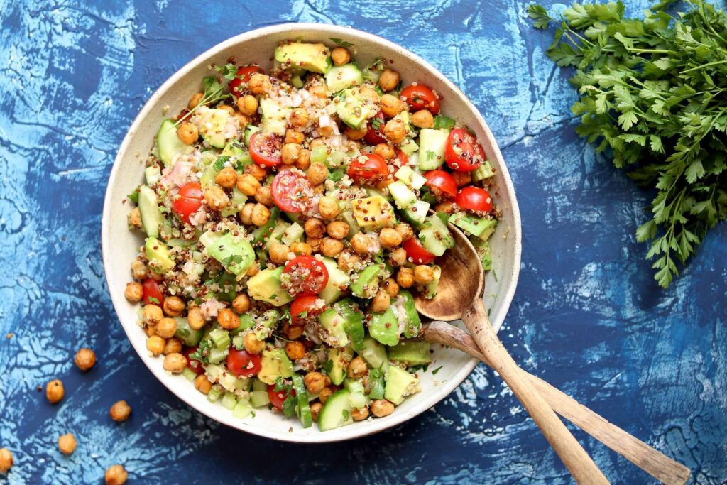 Fresh quinoa salad with mixed greens, cherry tomatoes, cucumber, and feta cheese in a bowl