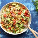 Fresh quinoa salad with mixed greens, cherry tomatoes, cucumber, and feta cheese in a bowl