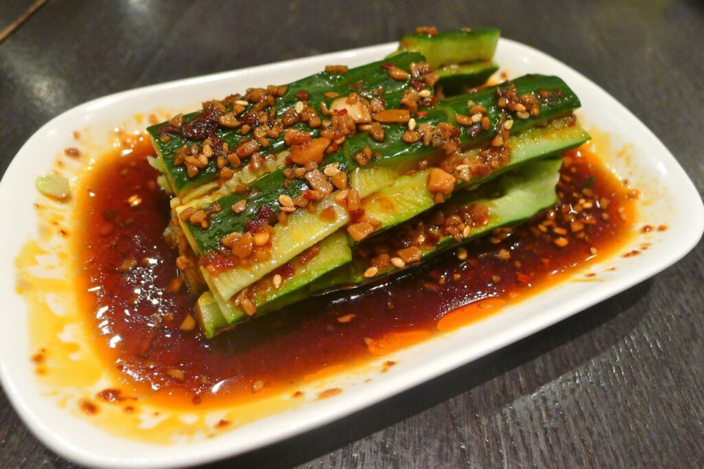 Din Tai Fung cucumber salad recipe served in a white plate with sesame seeds garnish.