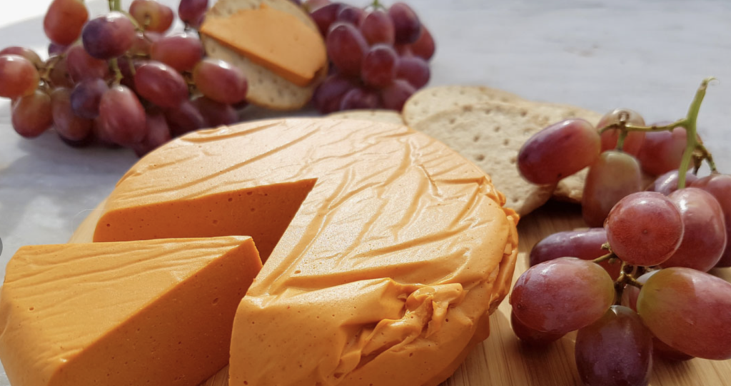 Delicious smoked queso dip in a cast wooden skillet surrounded by grapes