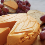 Delicious smoked queso dip in a cast wooden skillet surrounded by grapes