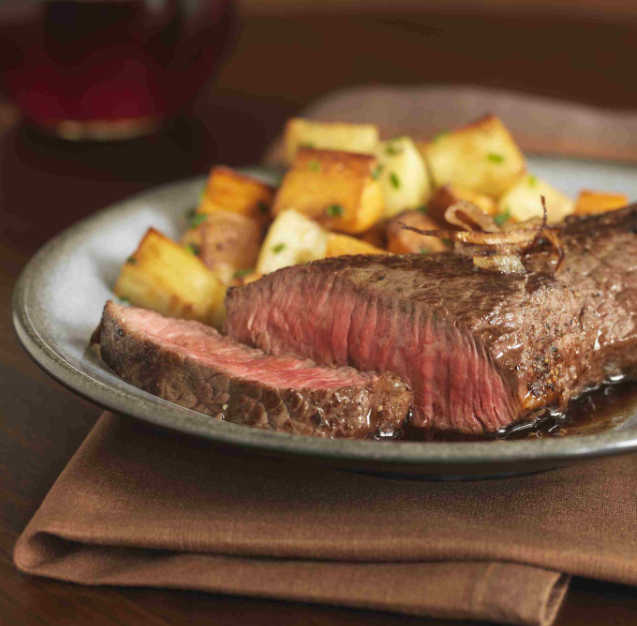 Juicy chuck steak served on a plate with herb butter and fresh herbs garnish