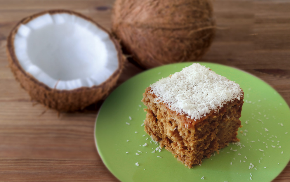 Close-up of a creamy coconut cake vape juice in a clear bottle with a dropper, displayed on a plate beside vanilla pods and fresh coconuts, embodying the essence of the coconut cake vape recipe.