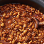 Delicious homemade baked beans in a ceramic dish, garnished with fresh herbs