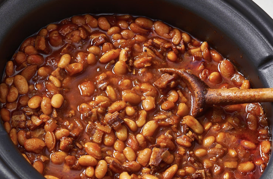 Delicious homemade baked beans in a ceramic dish, garnished with fresh herbs