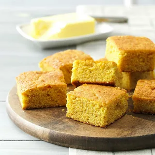 Freshly baked Southern cornbread in a round dish, golden and crispy on the outside, served on a rustic wooden table.